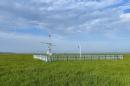 Scientific instruments sit in a green field below a blue sky.